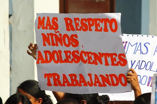Enfants brandissant une affiche écrite en rouge et en espagnol "Plus de respect enfants adolescents travaillant".