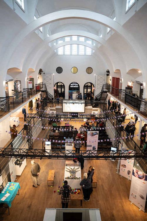 Prise depuis l'étage, la photo montre l'intérieur du musée faiblement éclairé, avec des personnes déambulant et regardant les expositions.